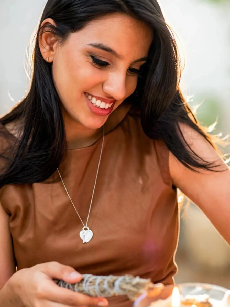 Sensitiva Marcelli sorrindo, com um maço de ervas na mão ao lado de uma vela acesa